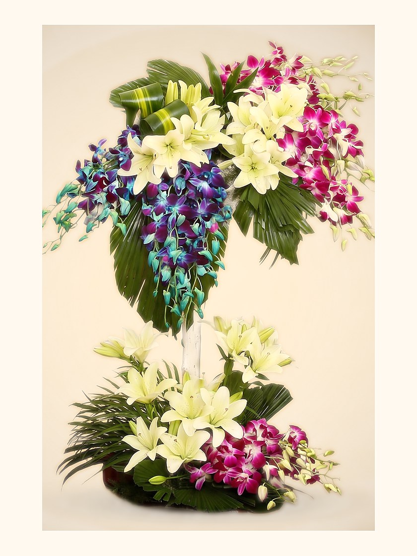 A tall two-tier arrangement of orchids and lilies