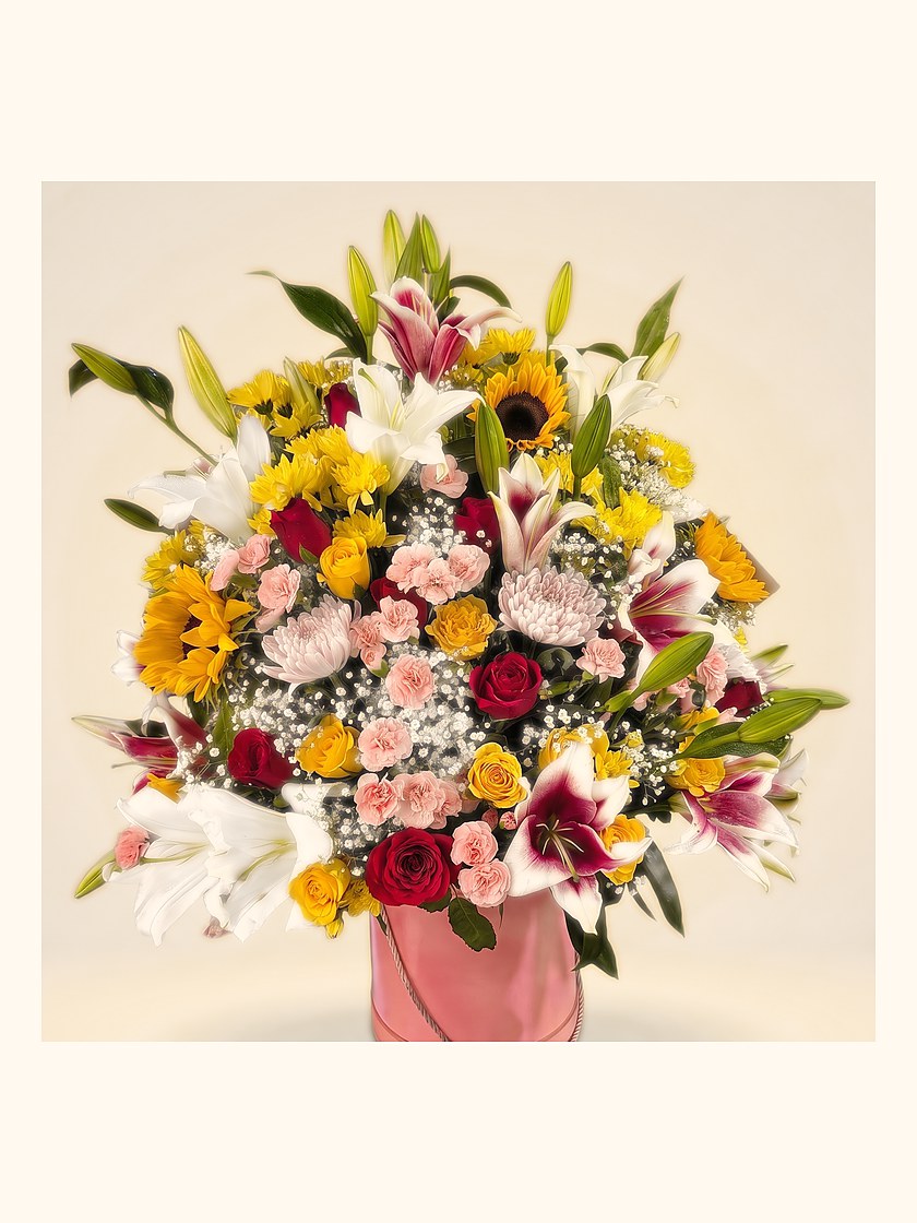 A large arrangement of lilies, roses and sunflowers in a pink wrap