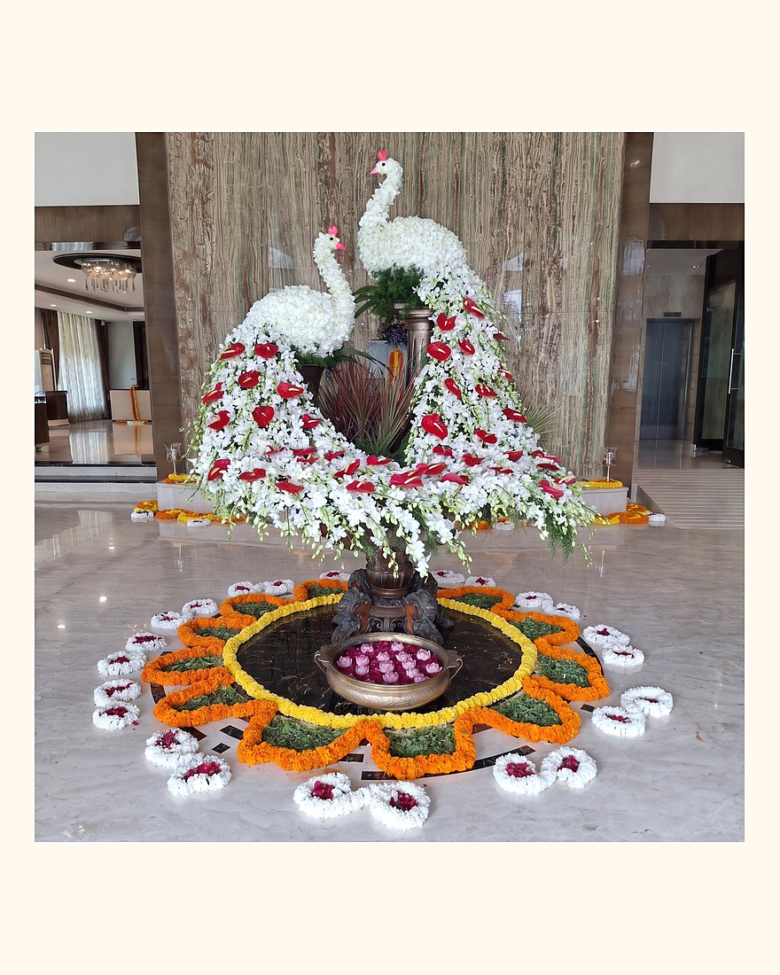 A peacock made of flowers above a marigold rangoli in a hotel lobby