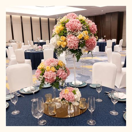 A tall table centrepiece of pink and yellow blooms at a banquet