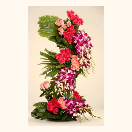 A vertical column of orchids, roses and palm leaves