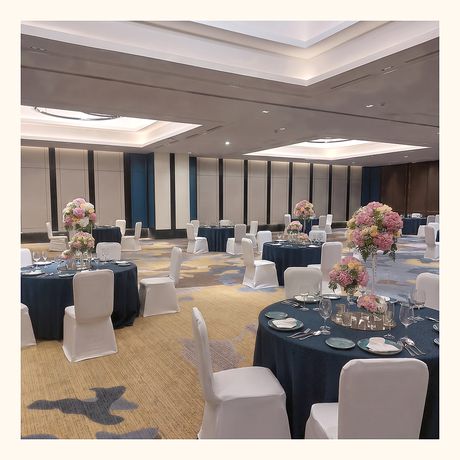 A banquet hall laid out with flower centrepieces on every table